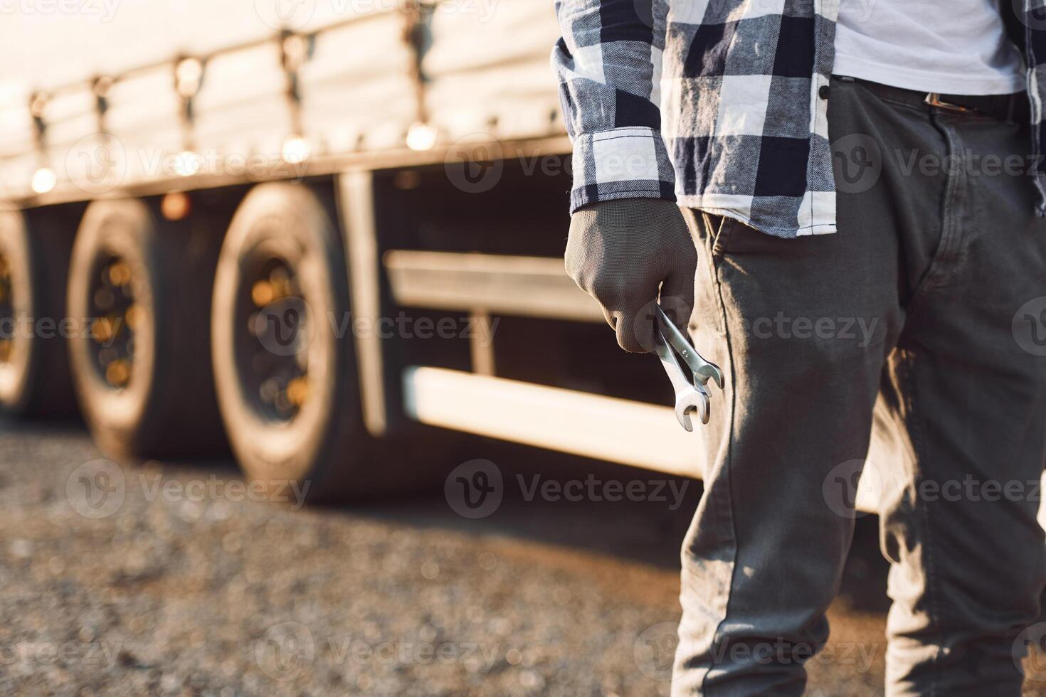 Close up view.. Young truck driver is with his vehicle at daytime photo
