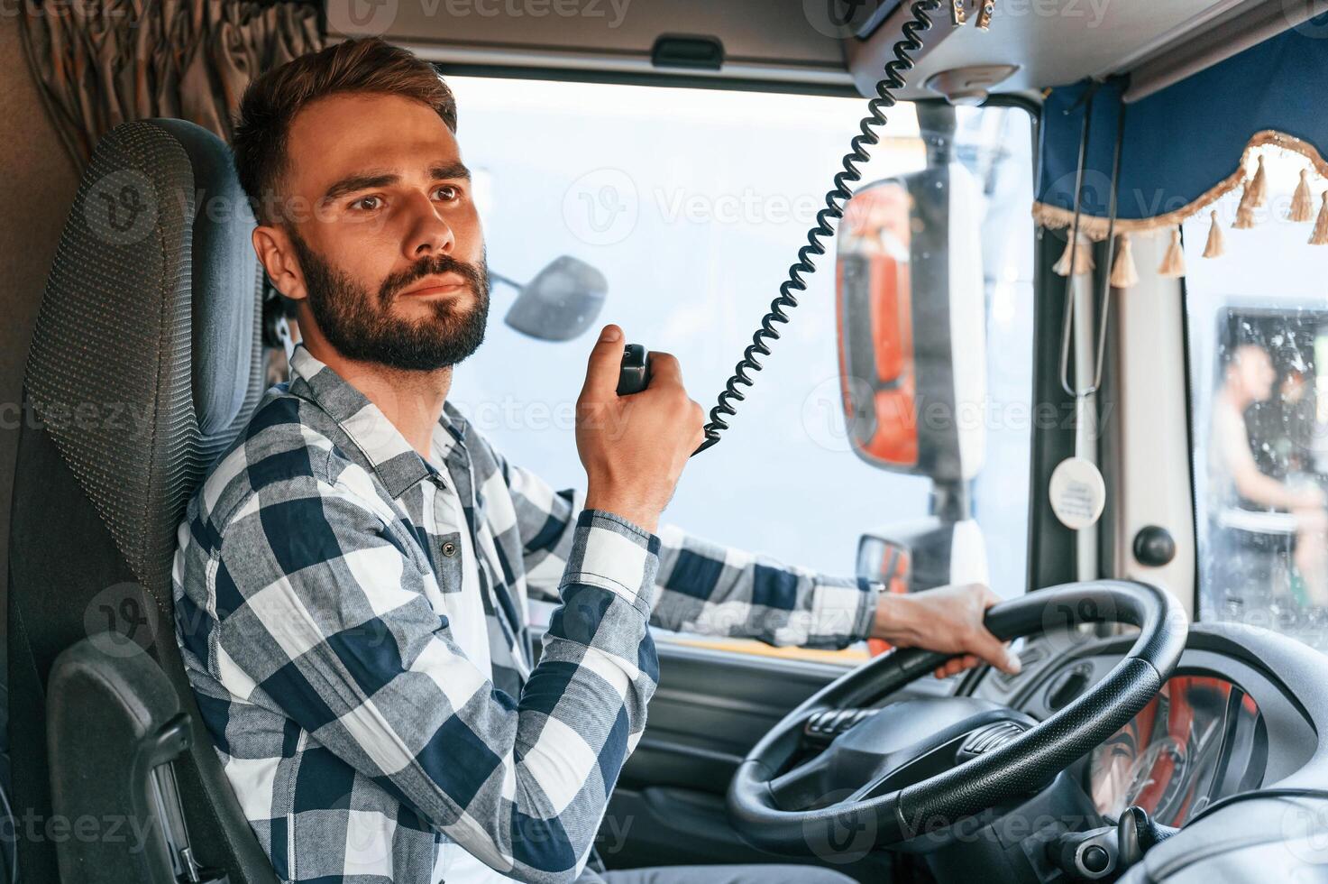 Using radio. Young truck driver is with his vehicle at daytime photo