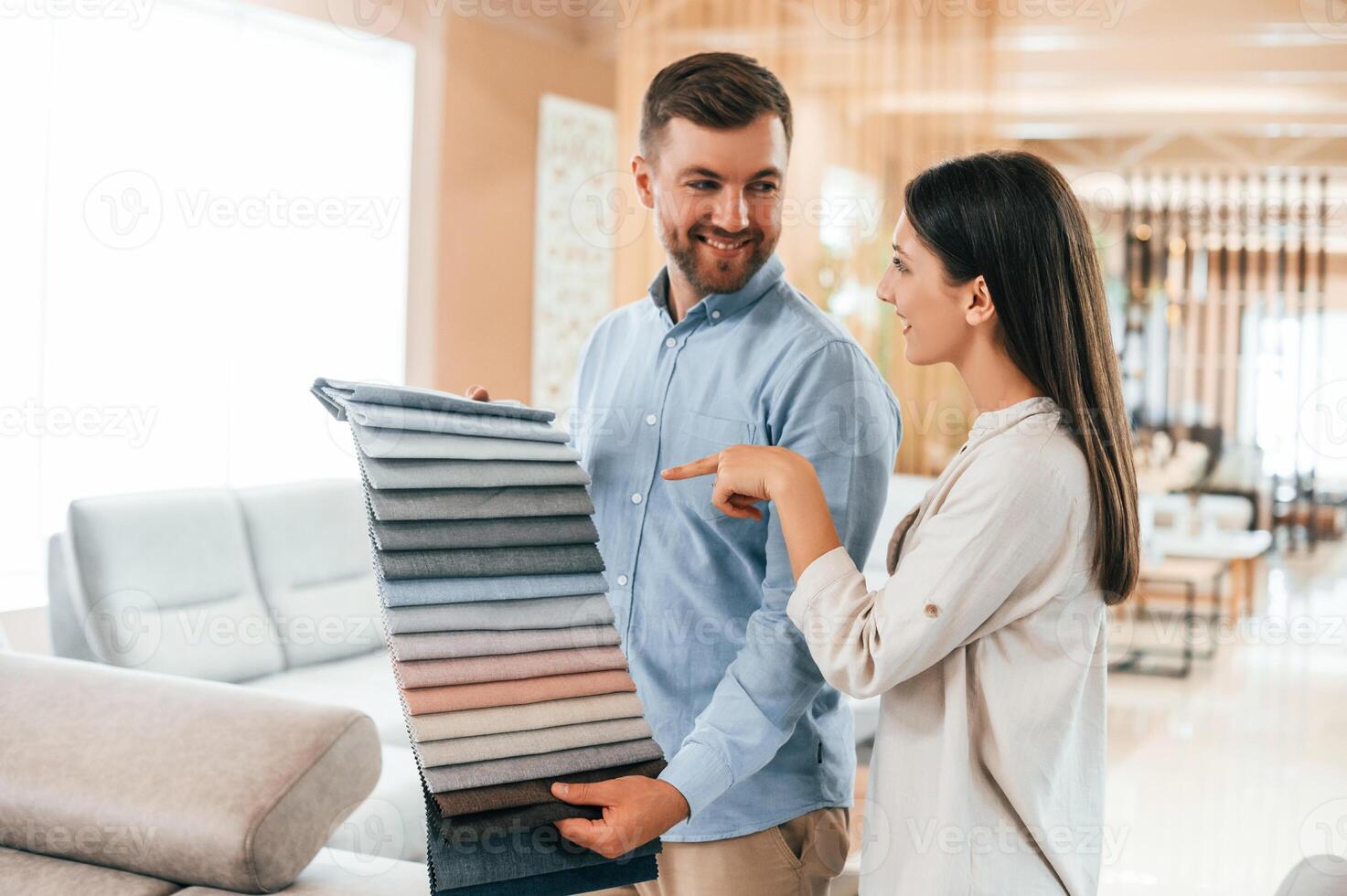 Looking for right color.. Couple choosing the sofa and bed in the store photo