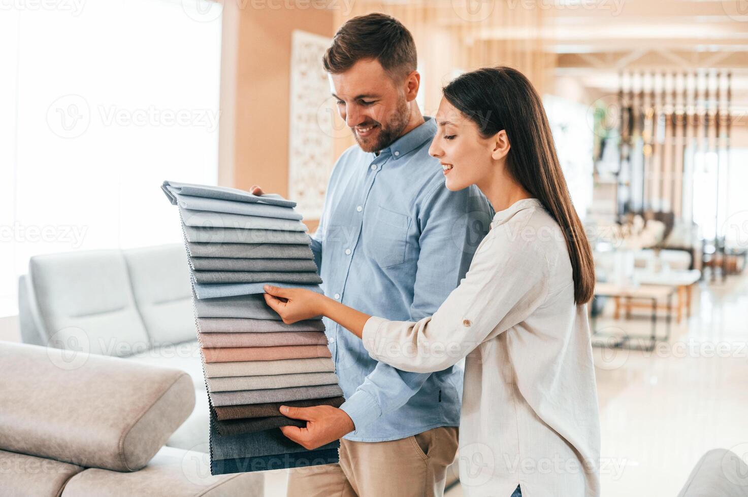 Looking for right color. Couple, choosing the sofa and bed in the store photo