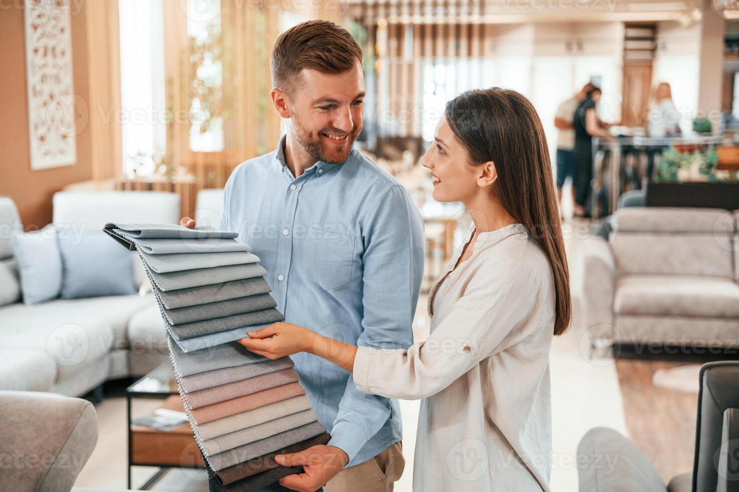 Man holding ,different colored materials to choose from. Couple looking for the sofa and bed in the store photo