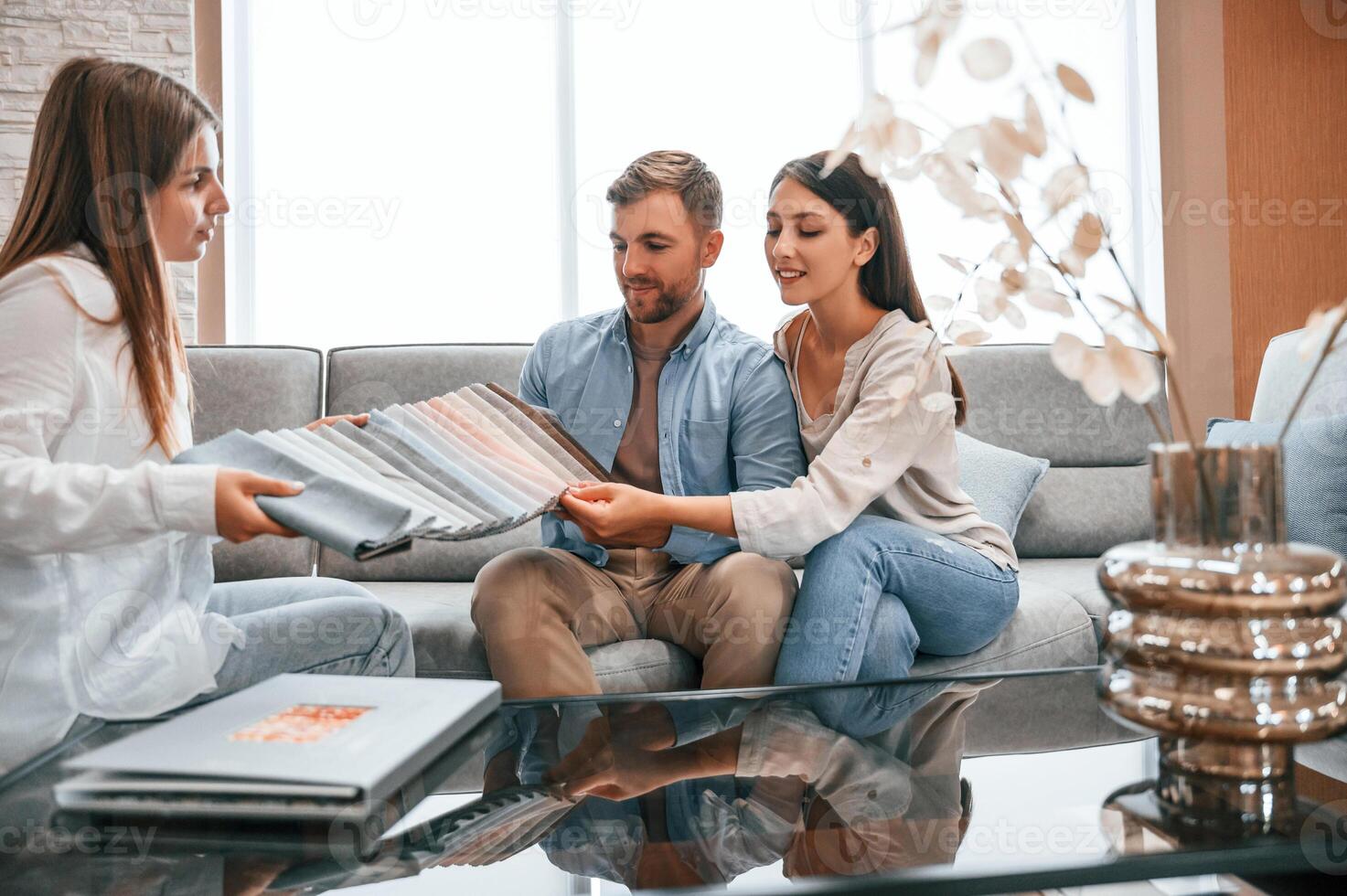 Looking at the catalogue. Woman ,helping couple with choosing the sofa and bed in the store photo