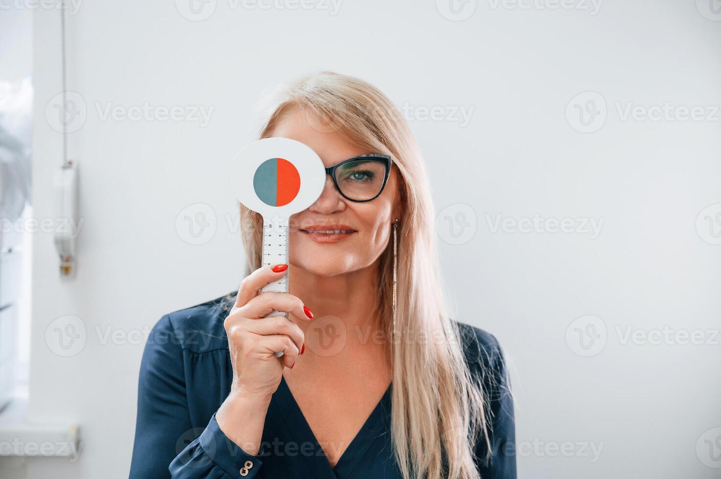 Woman sitting in the clinic and covering her eye. Testing vision photo