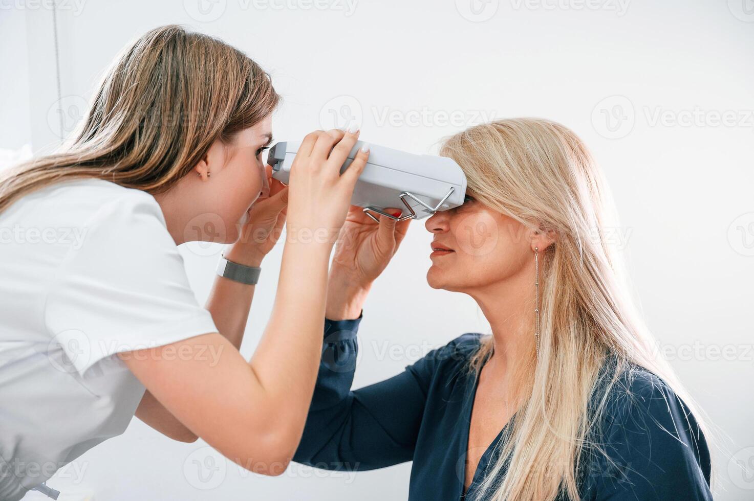 Woman's vision is tested, by clinic worker that using special device photo