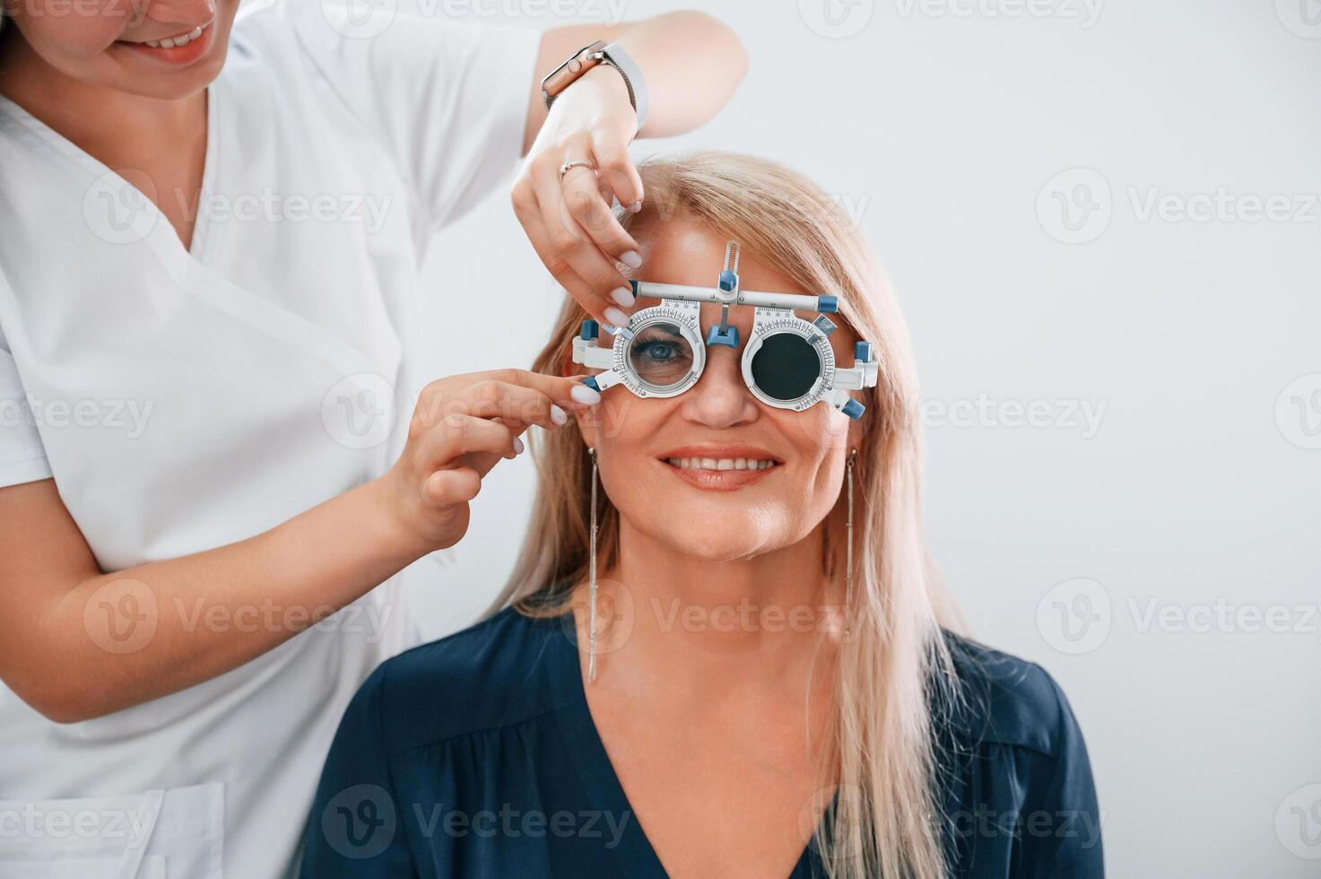 Wearing glasses. Woman's vision is tested by clinic worker that using special device.. photo