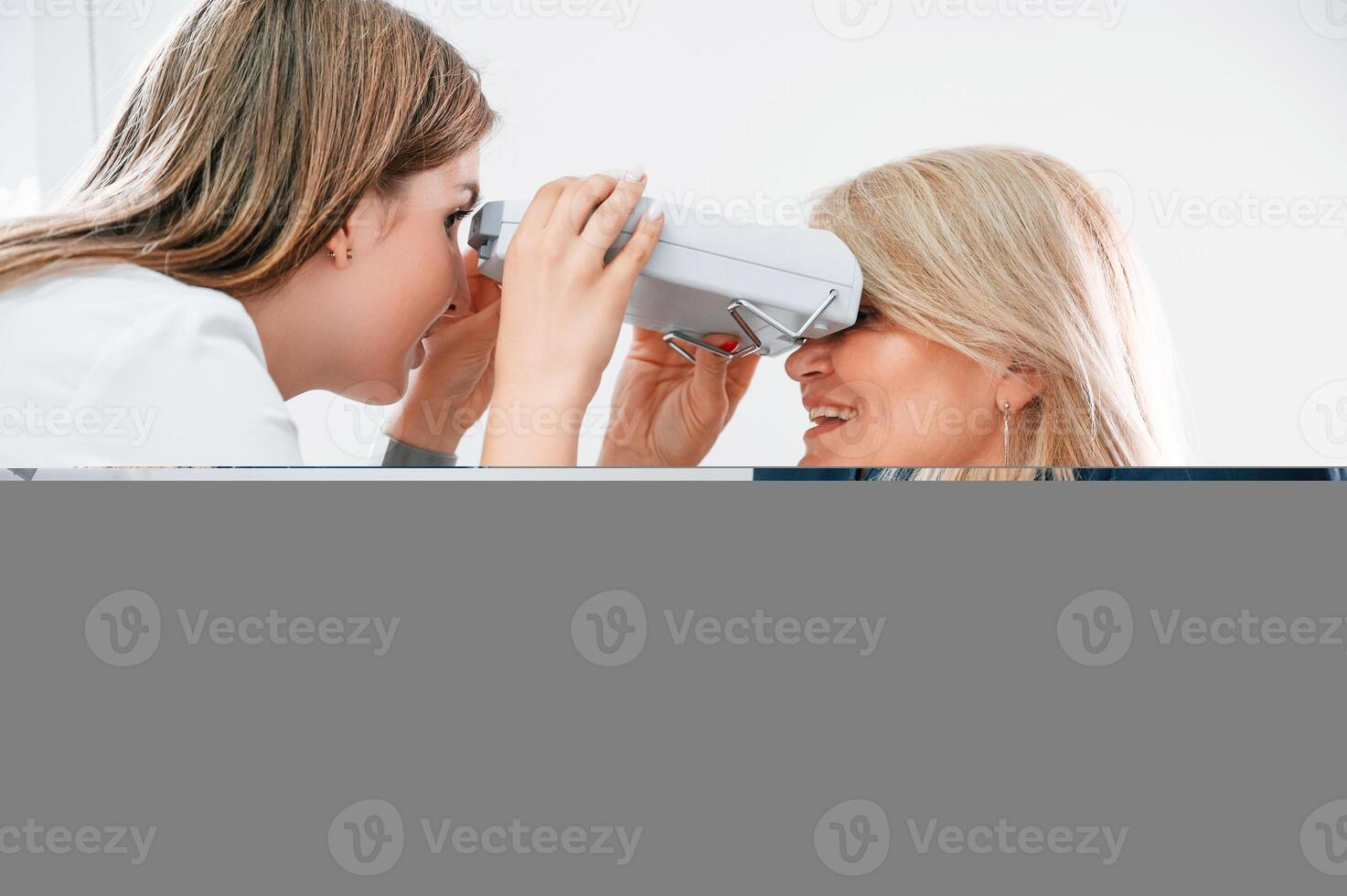 Woman's vision ,is tested by clinic worker that using special device photo