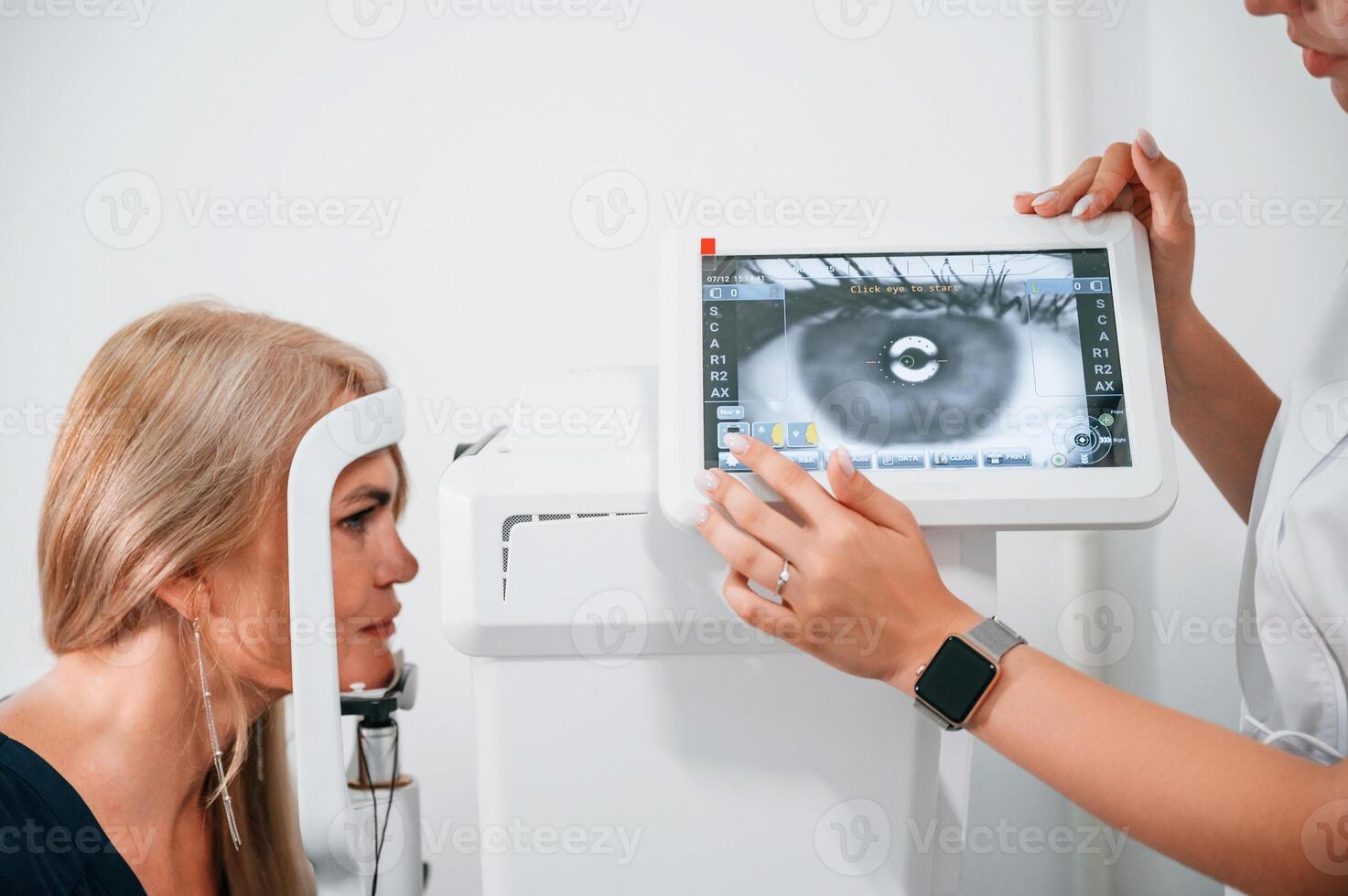 Side, view. Woman's vision is tested by clinic worker that using special device photo