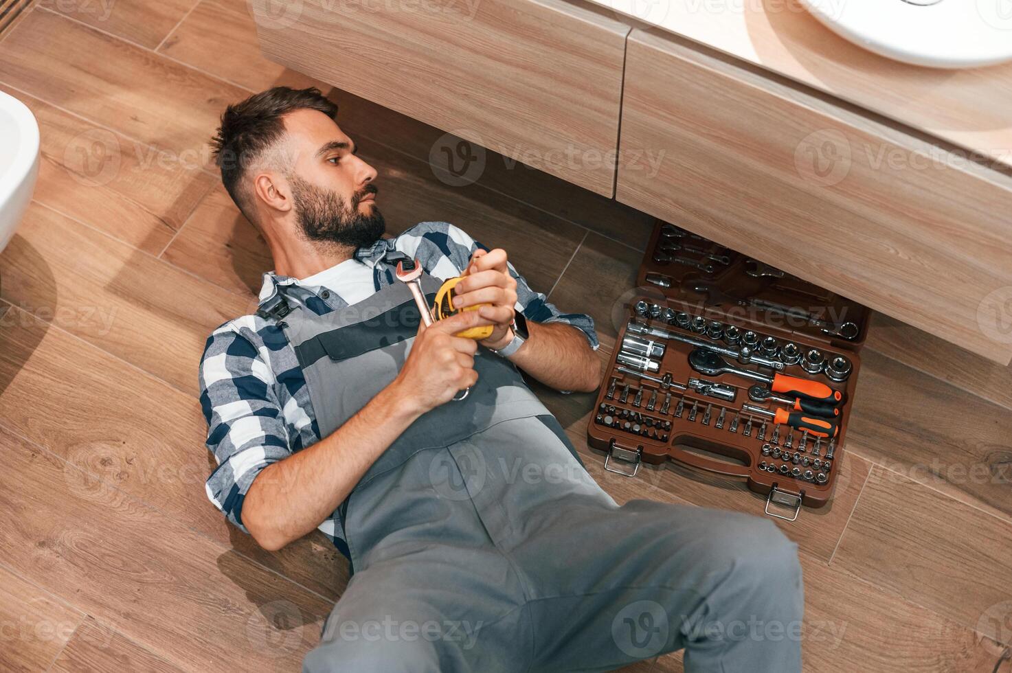 Plumber in uniform is indoors at home photo