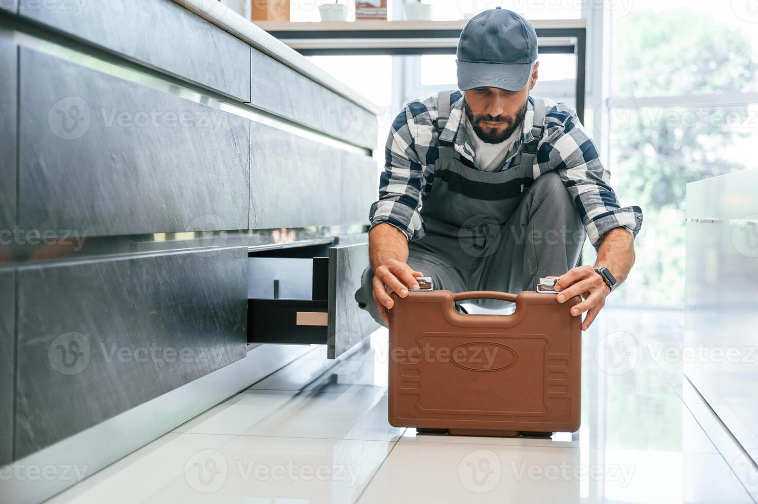 Case with equipment. Plumber ,in uniform is indoors at home photo