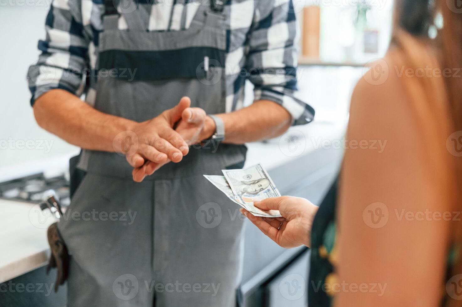 Close up view. Plumber, receiving cash for the work he is done on the kitchen photo