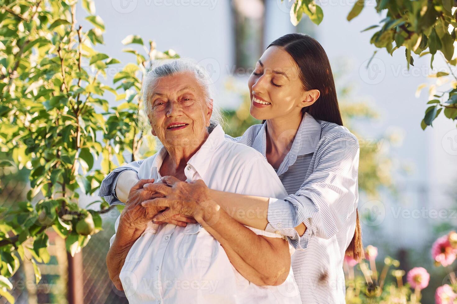 Standing in ,the beautiful garden and embracing each other. Young woman is with her senior mother photo