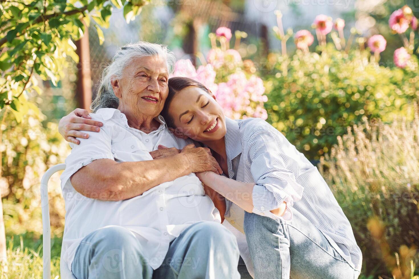 Sitting ,and embracing each other. Young woman is with her senior mother is in the garden photo