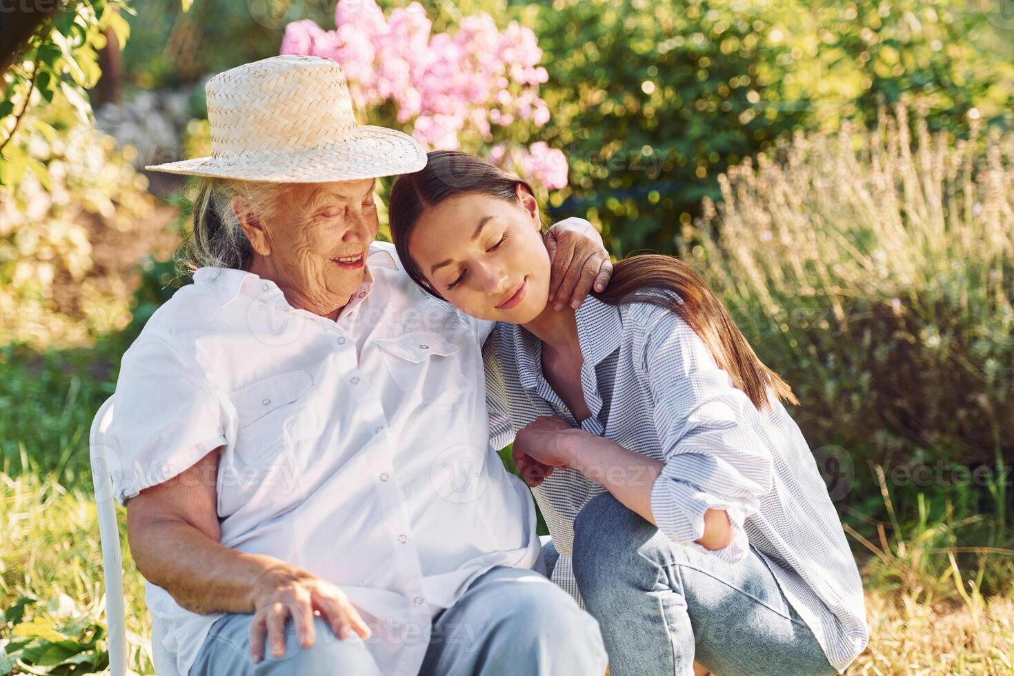 Sitting together.. Young woman is with her senior mother is in the garden photo