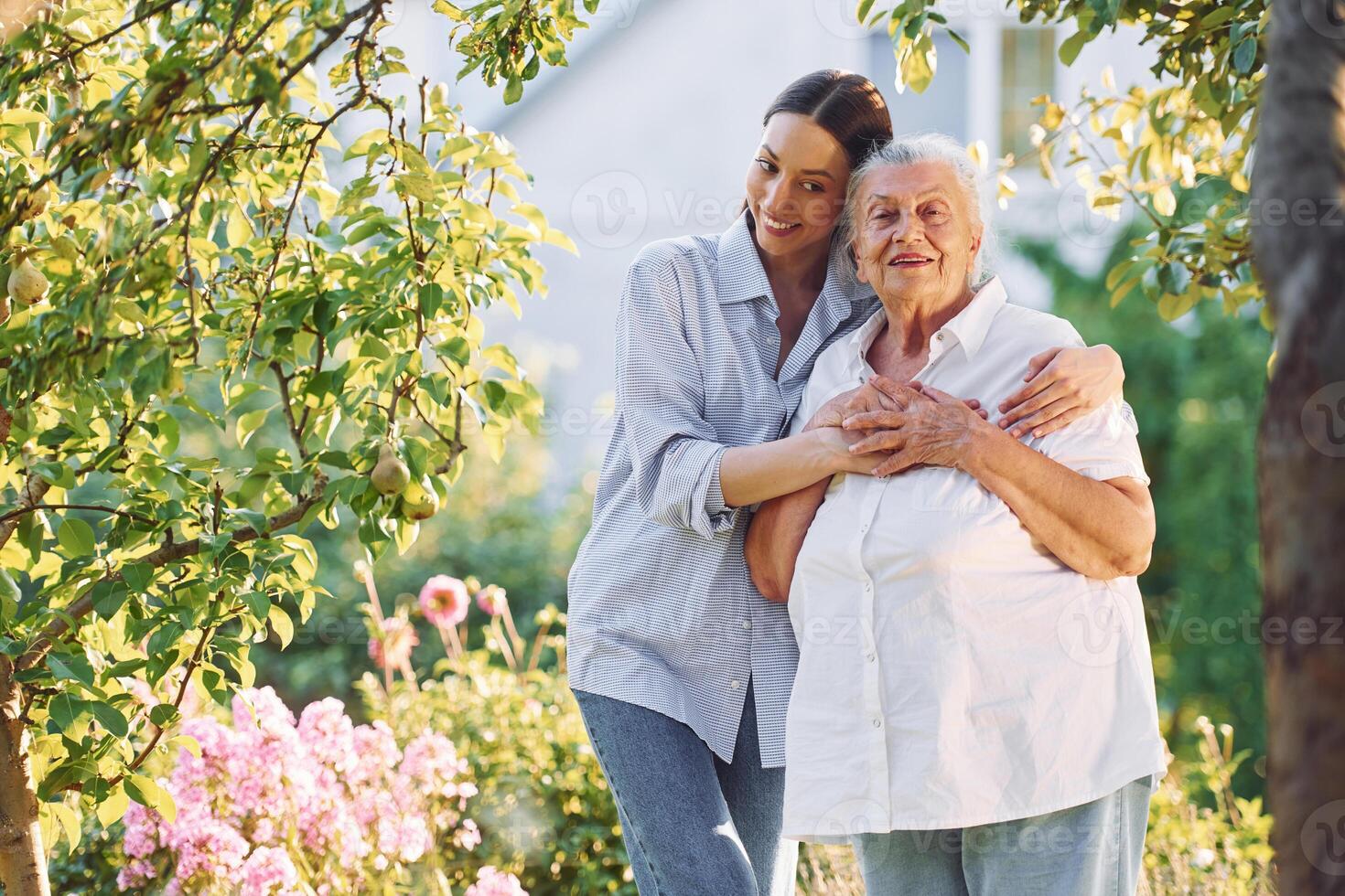 Embracing ,and smiling.. Young woman is with her senior mother is in the garden photo