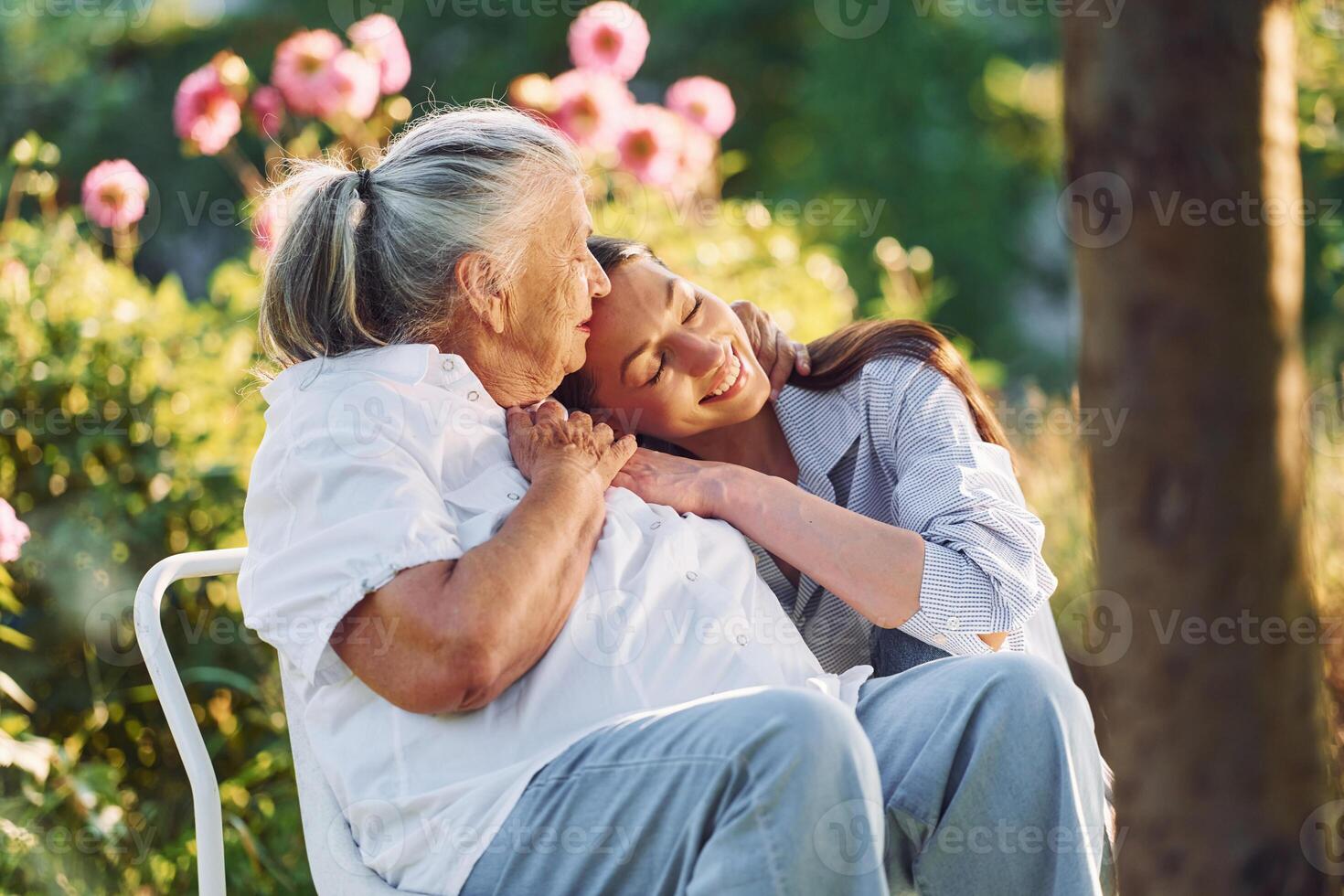 Sitting, and embracing each other. .Young woman is with her senior mother is in the garden photo