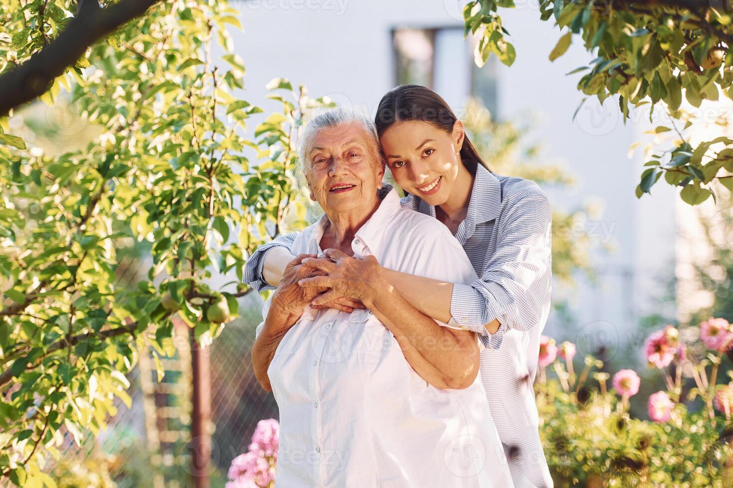 Standing in the beautiful ,garden and embracing each other. Young woman is with her senior mother photo