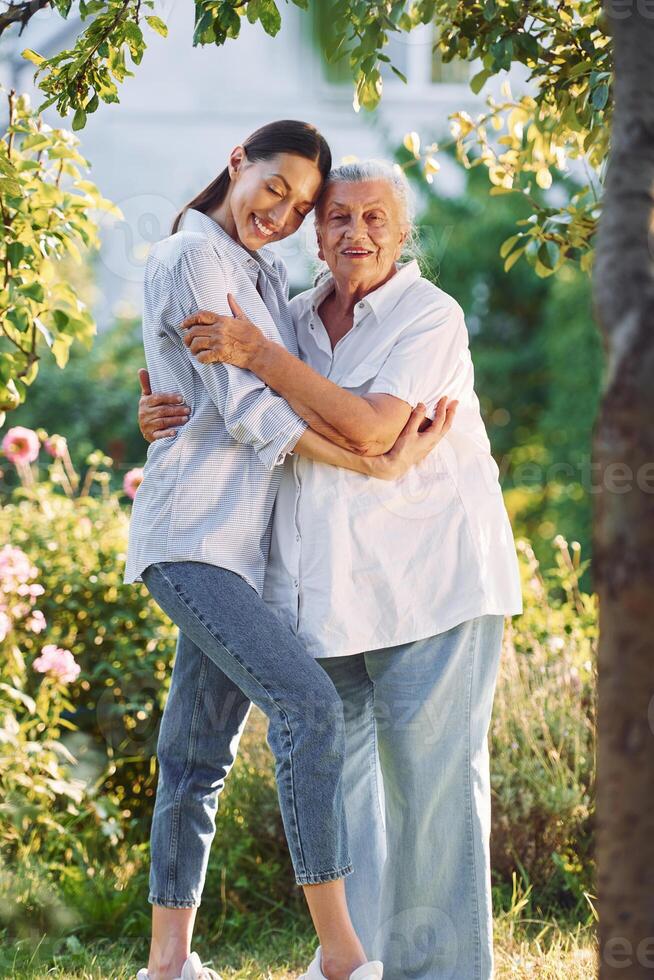 Conception, of love to a parent. Young woman is with her senior mother is in the garden photo