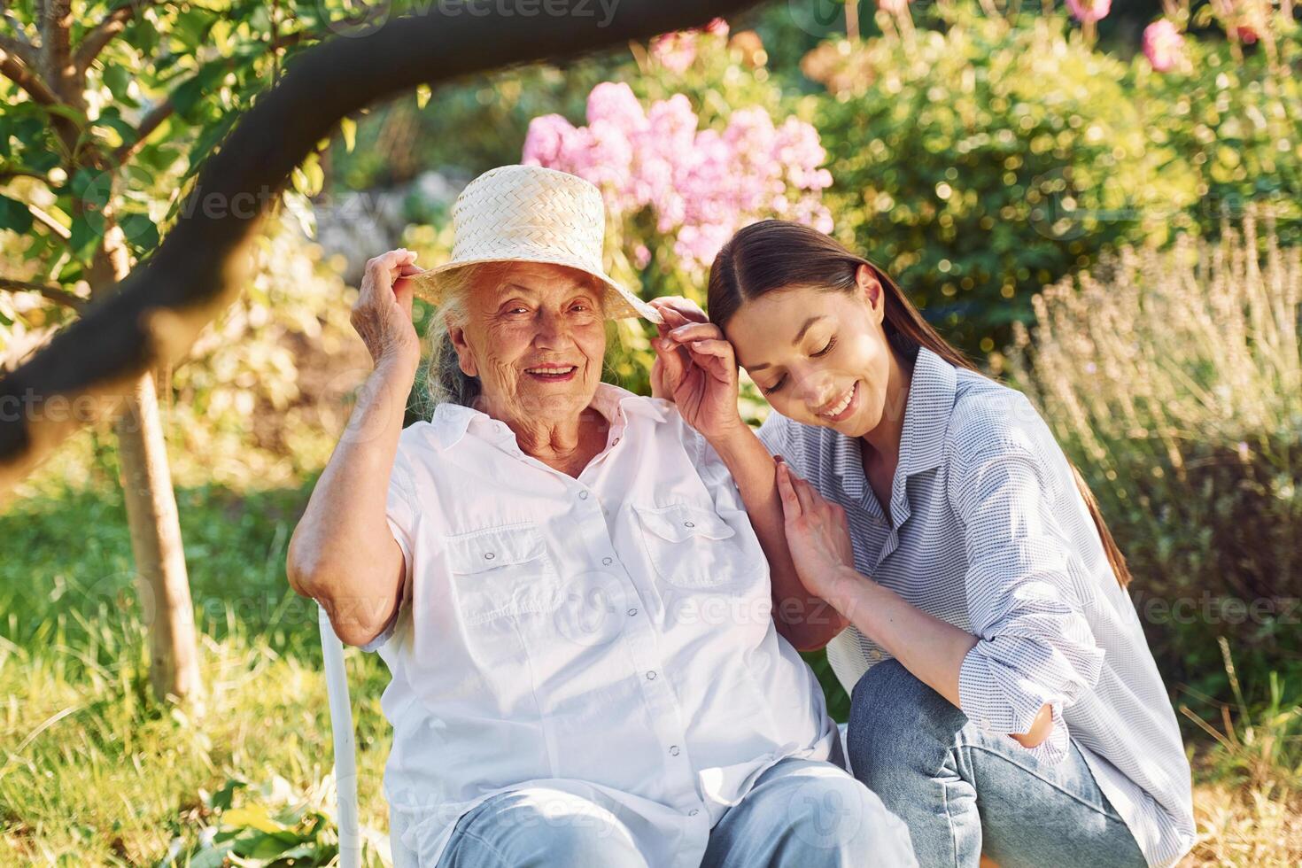 Sitting together. Young woman is with her senior mother is in the garden photo