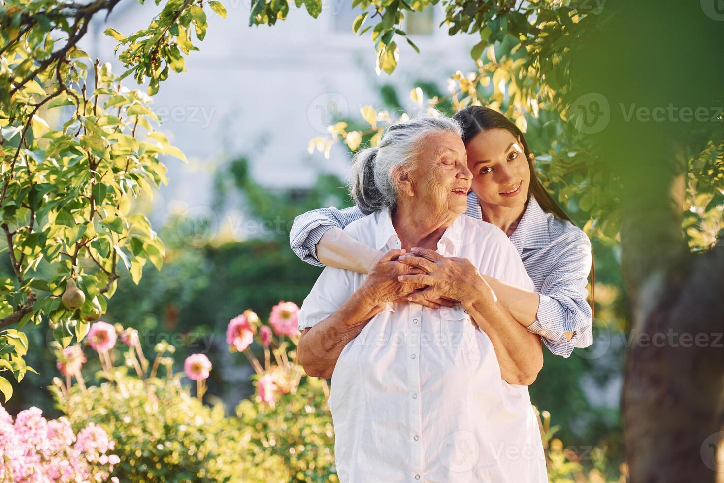 Standing in the beautiful garden, and embracing ,each other. Young woman is with her senior mother photo