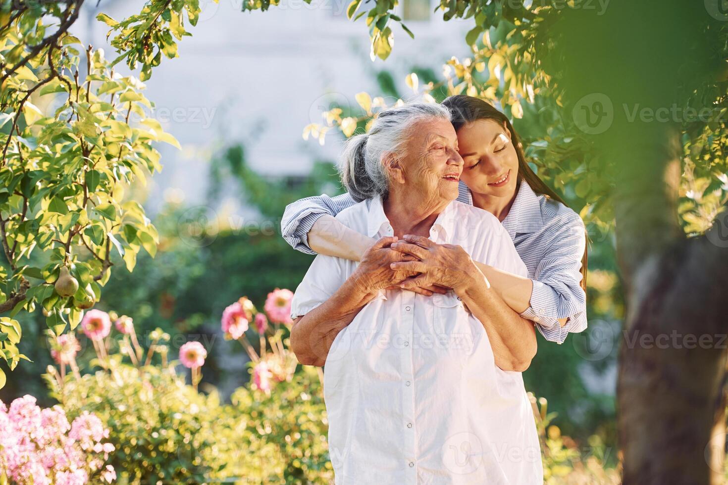 Standing ,in the beautiful garden and embracing ,each other. Young woman is with her senior mother photo