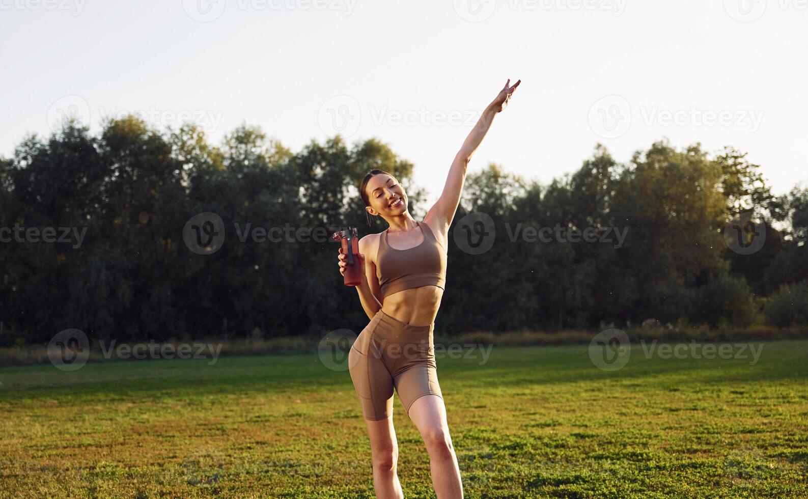 Beautiful nature. Young woman in yoga clothes is outdoors on the field photo