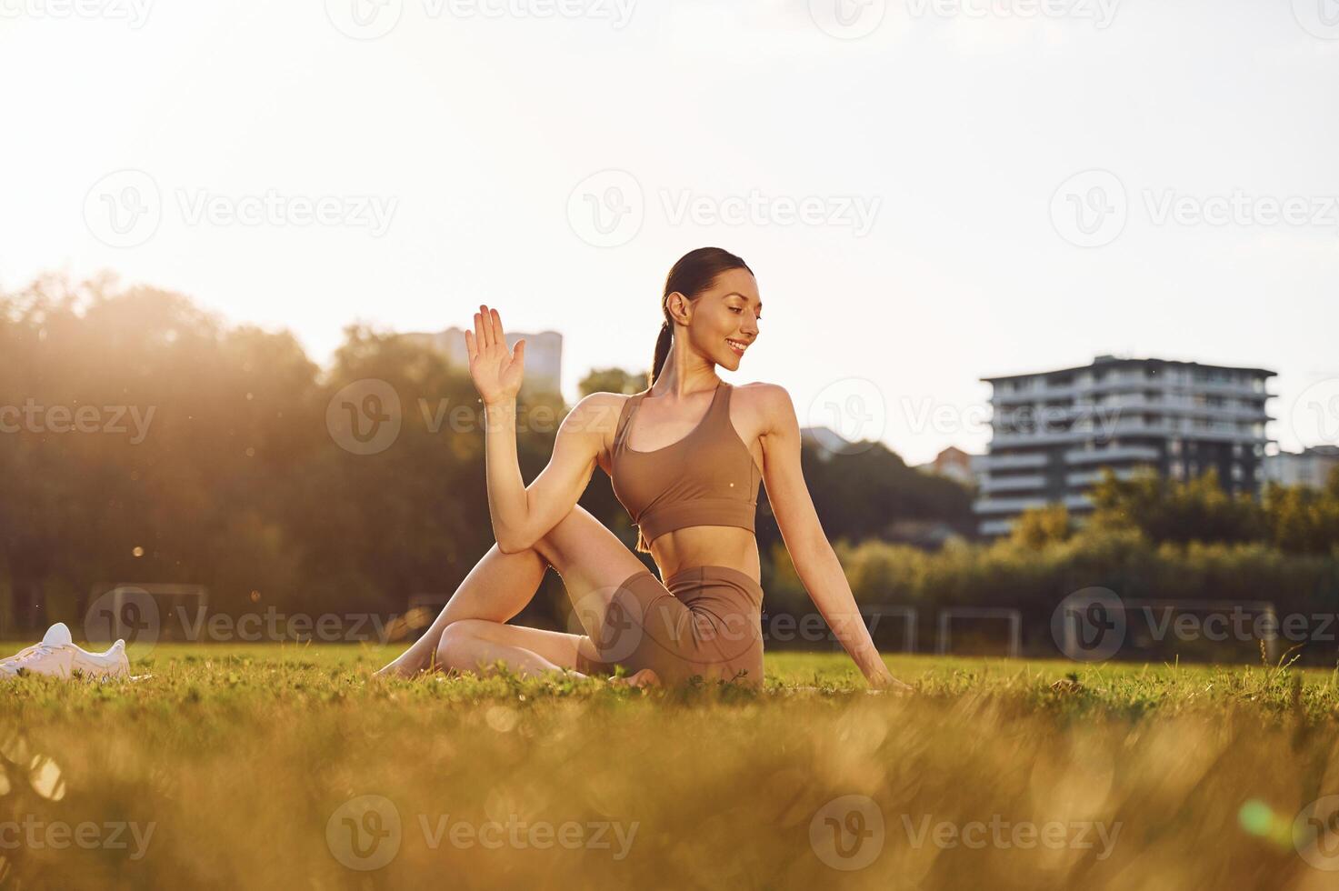 Doing yoga exercises. .Young woman in yoga clothes is outdoors on the field photo