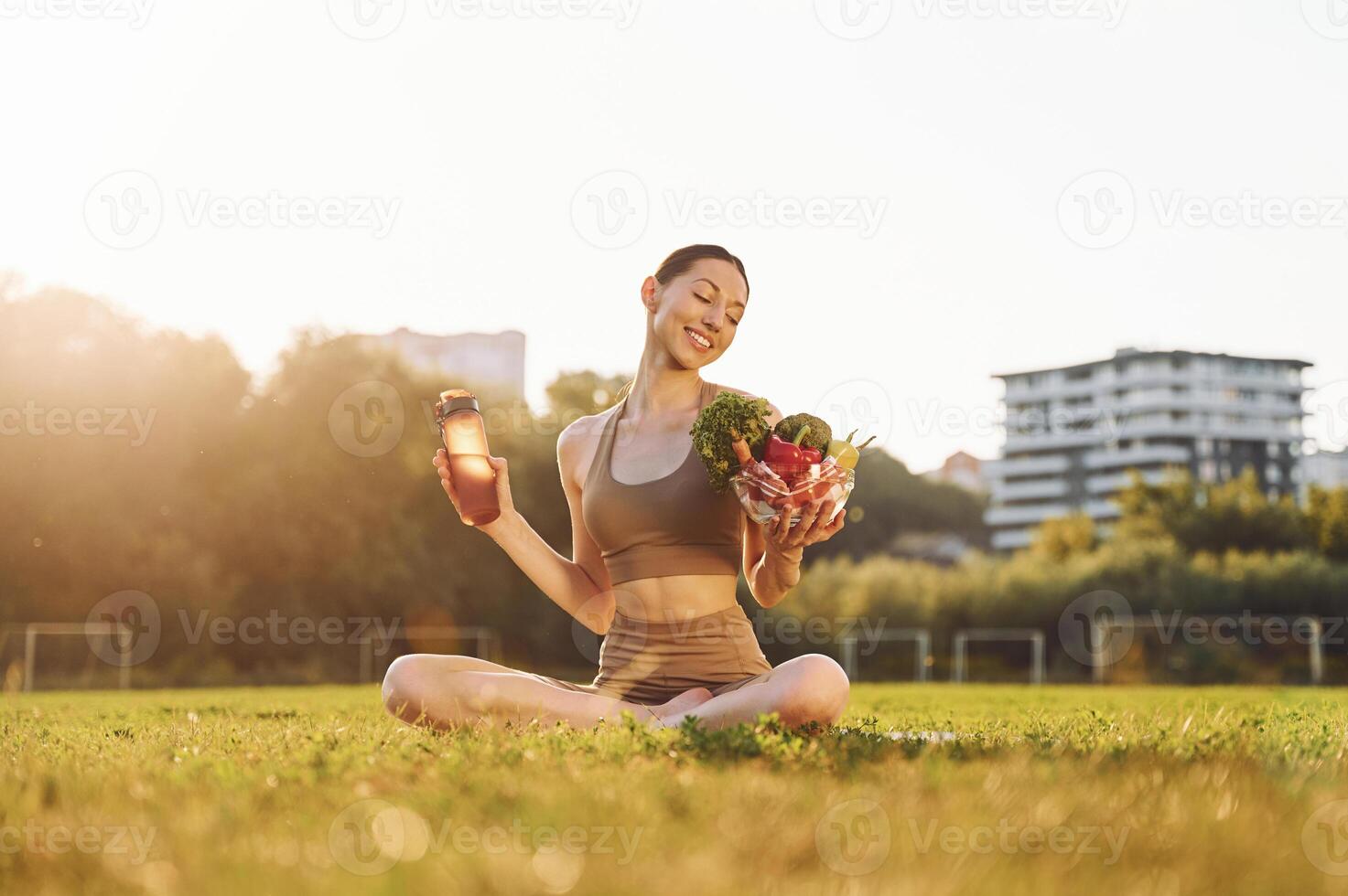 Diet conception. Healthy food. Young woman in yoga clothes is outdoors on the field photo