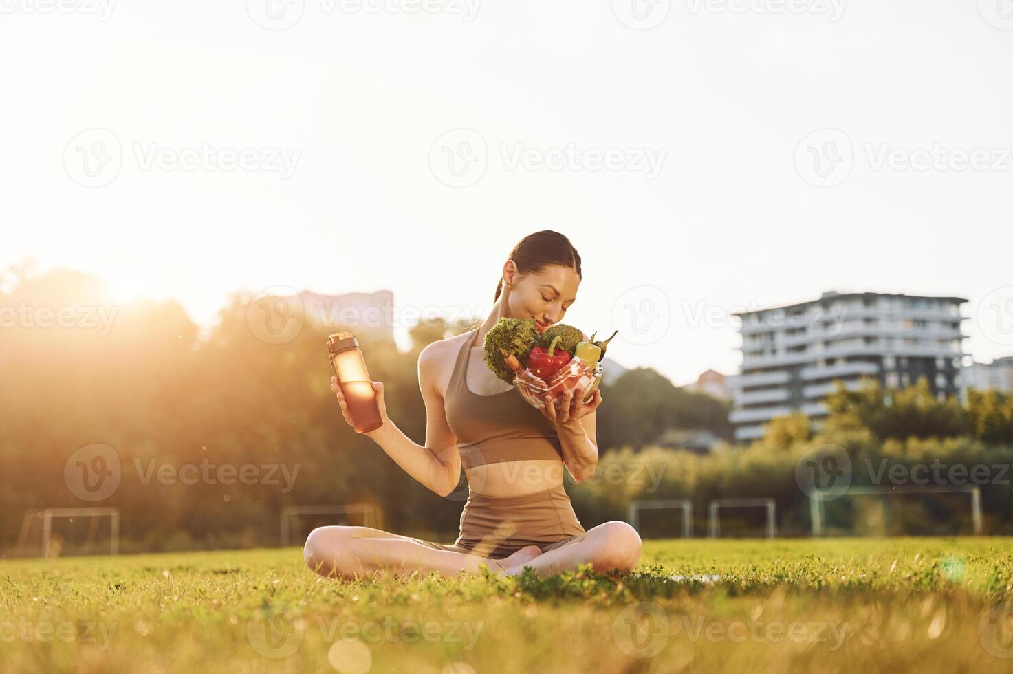 Conception of diet. Healthy food. Young woman in yoga clothes is outdoors on the field photo