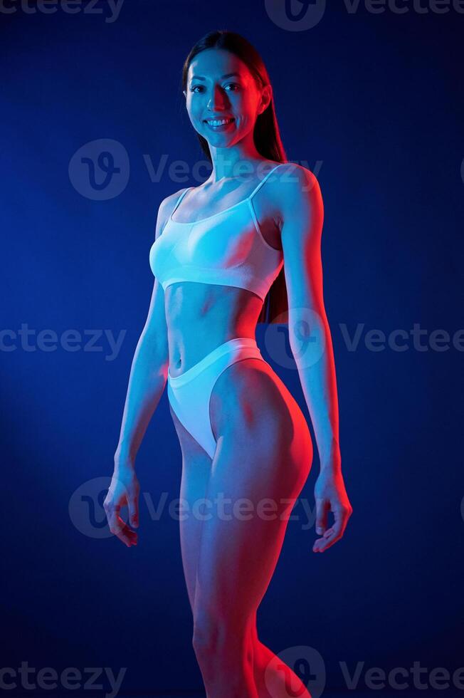 White top.. Young woman in underwear is in the studio with neon lights photo