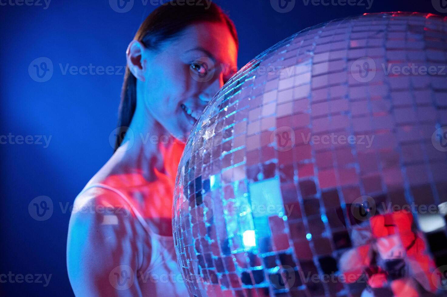 Holding, mirrored ball in the club. Young woman in underwear is in the studio with neon lights photo