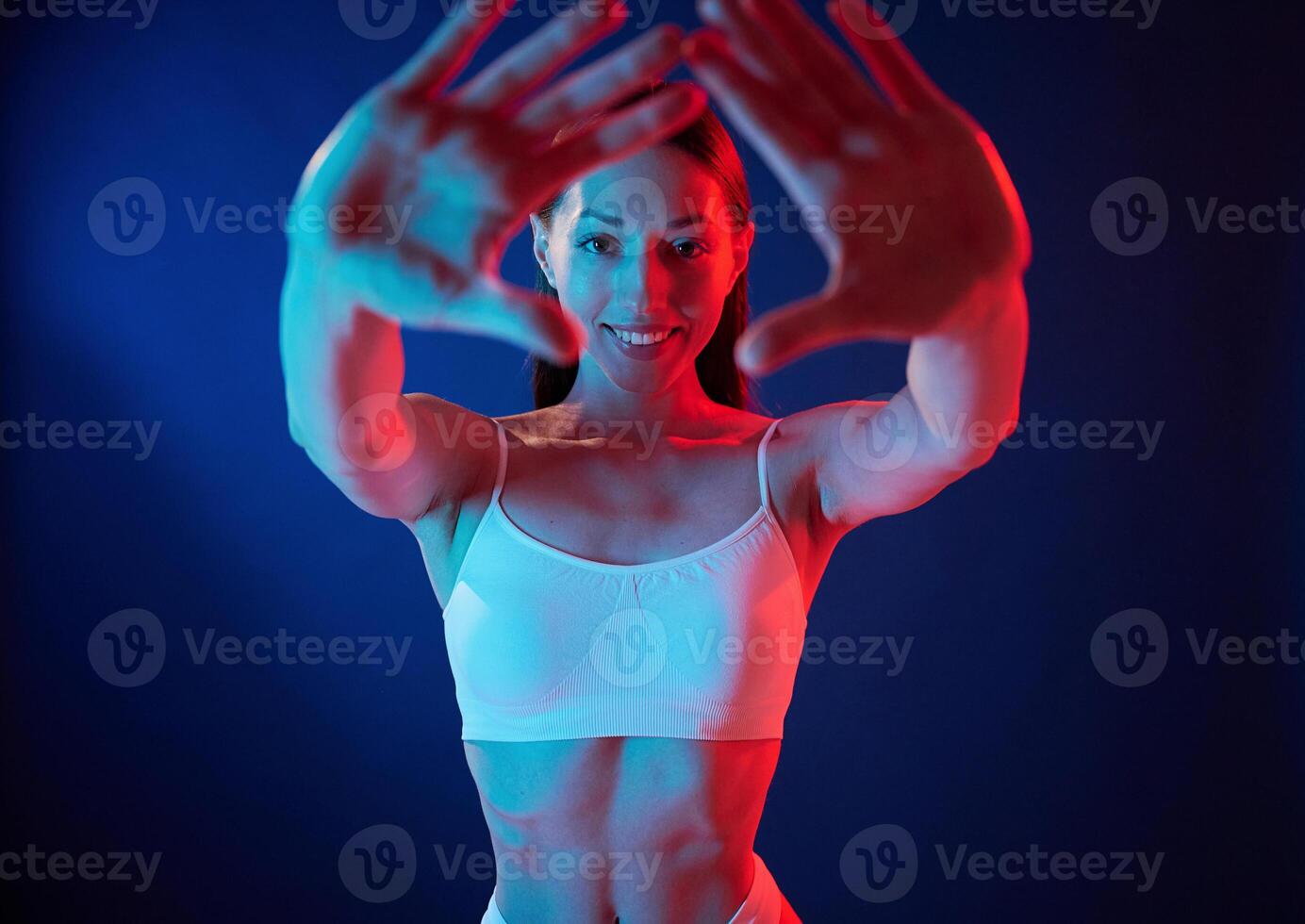 Doing, gestures by the hands. Young woman in underwear is in the studio with neon lights photo