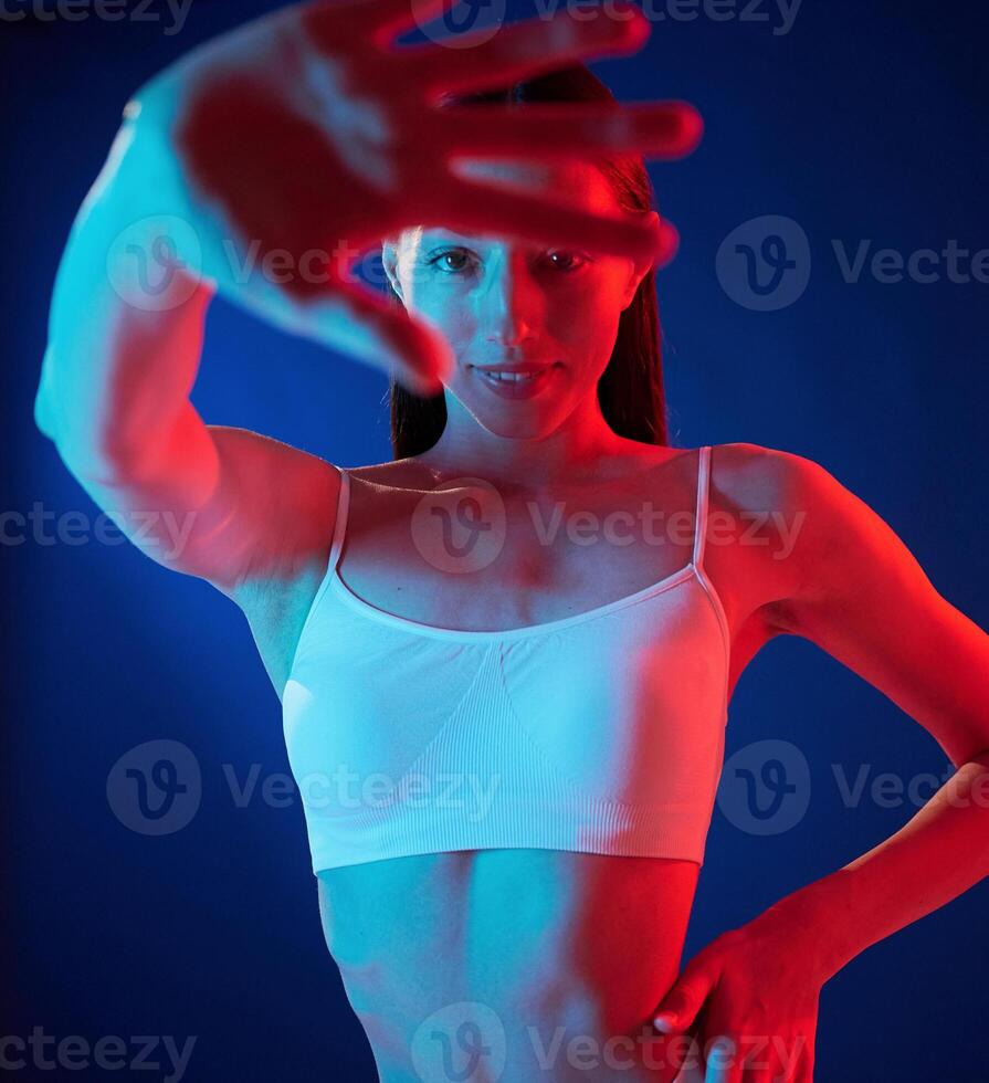 Doing, gestures ,by the hands. .Young woman in underwear is in the studio with neon lights photo