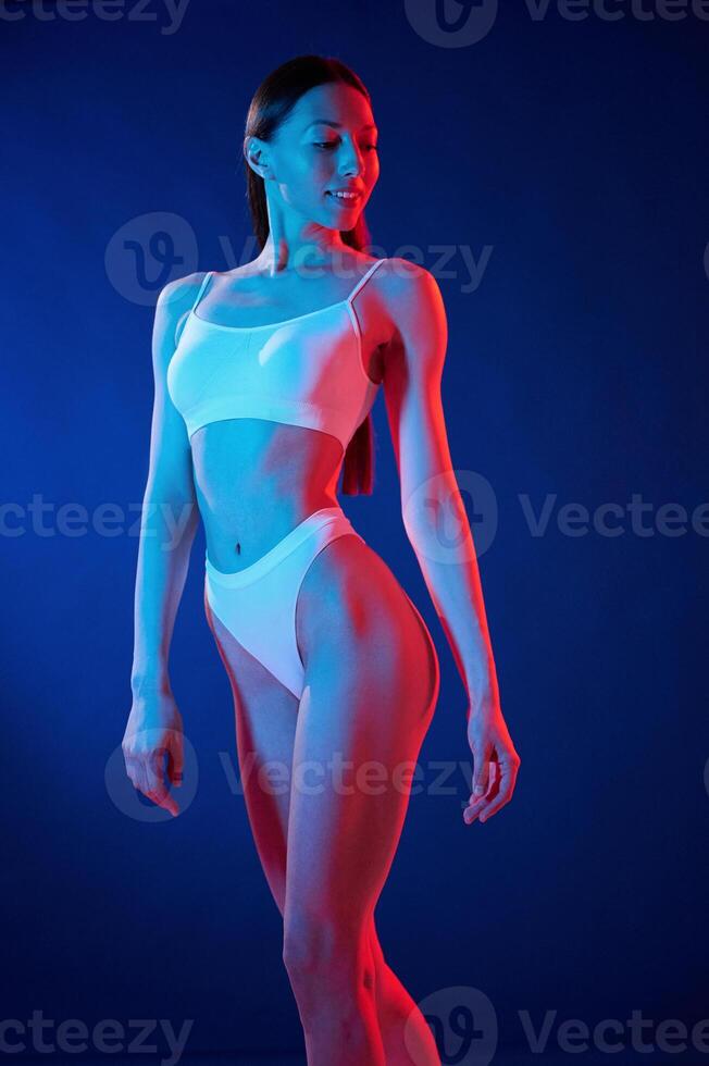 White top. Young woman in underwear is in the studio with neon lights photo