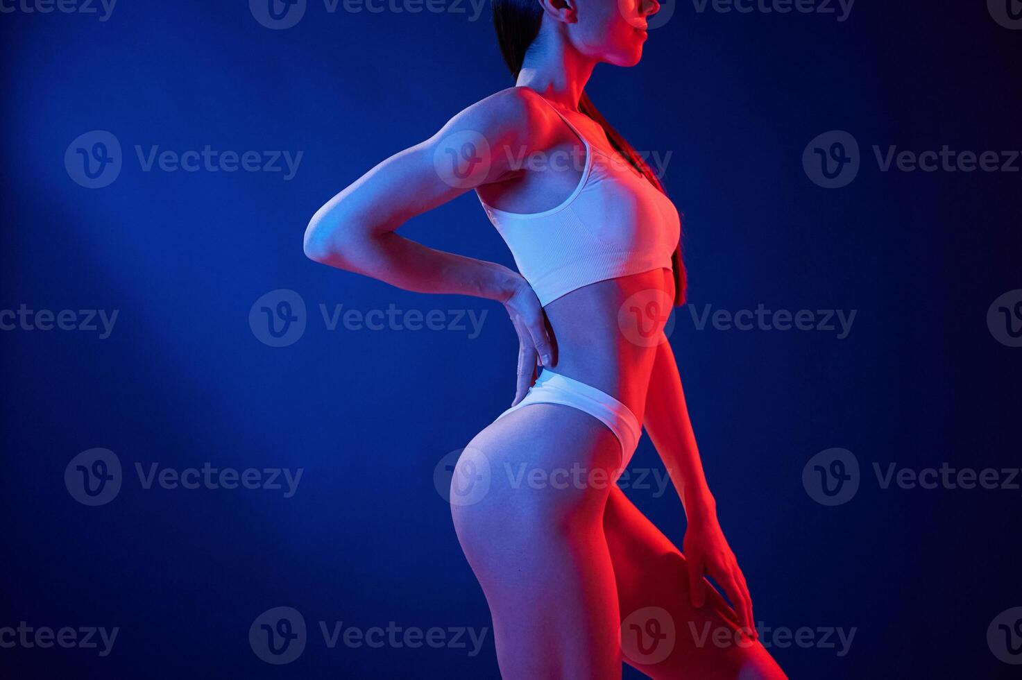 Blue, and red colors. Young woman in underwear is in the studio with neon lights photo