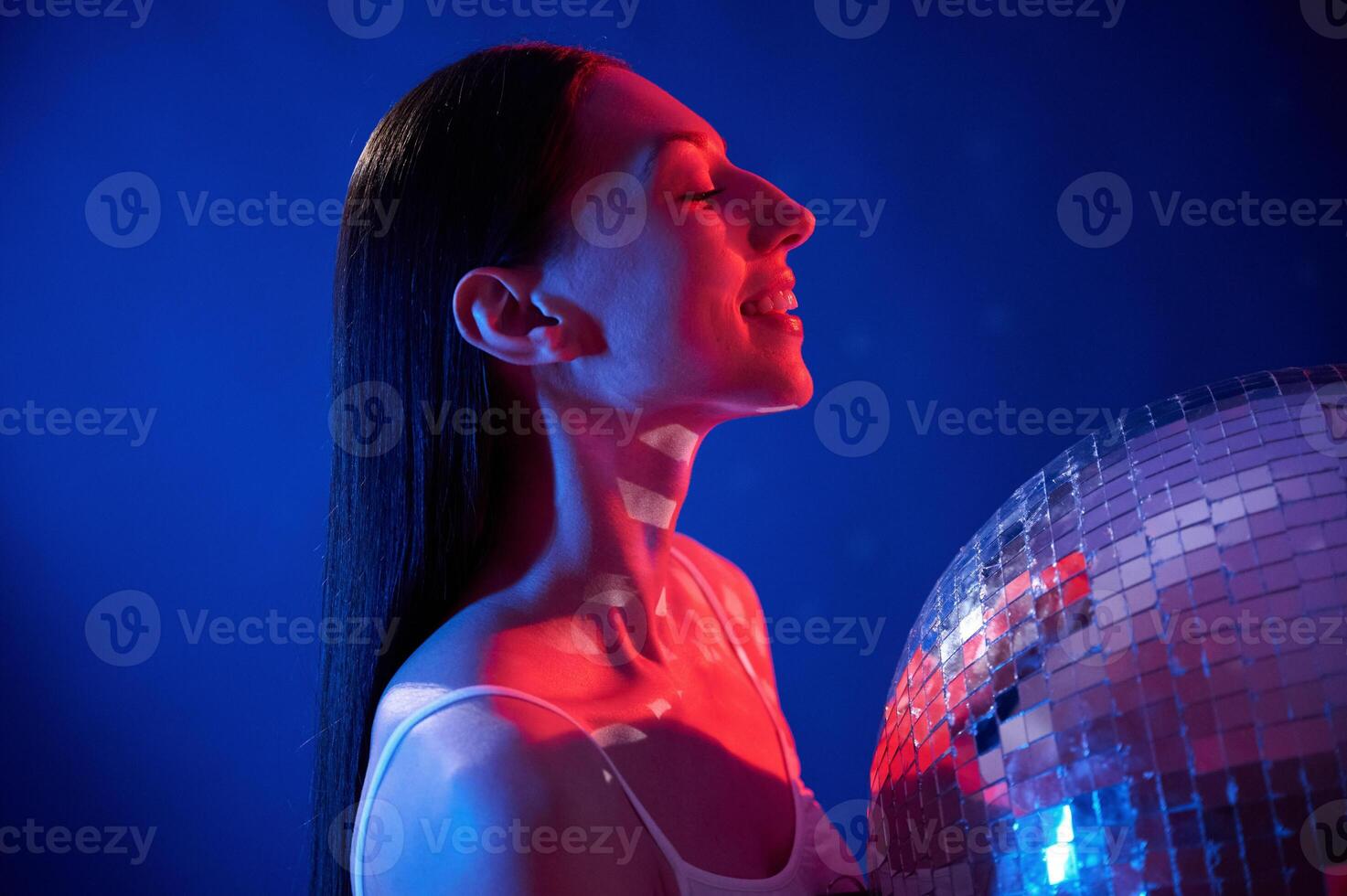 Holding ,mirrored ball in the club. Young woman in underwear is in the studio with neon lights photo