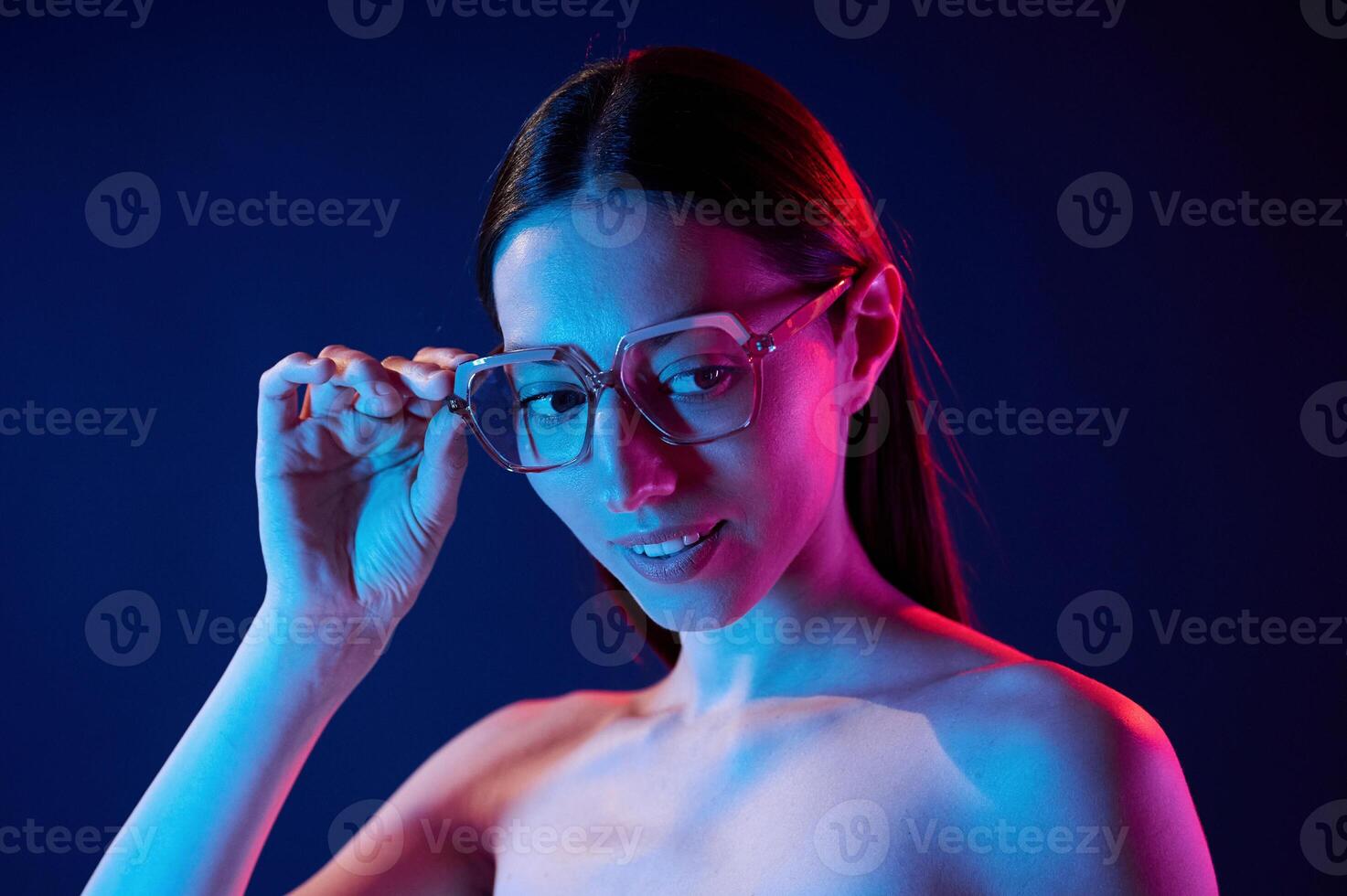 Wearing glasses.. Portrait of young woman that is indoors in neon lighting photo
