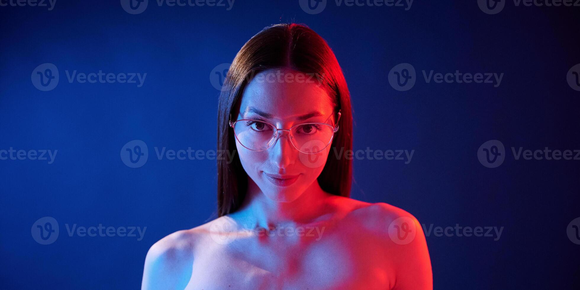 Conception of bad sight, in glasses. Portrait of young woman that is indoors in neon lighting. photo