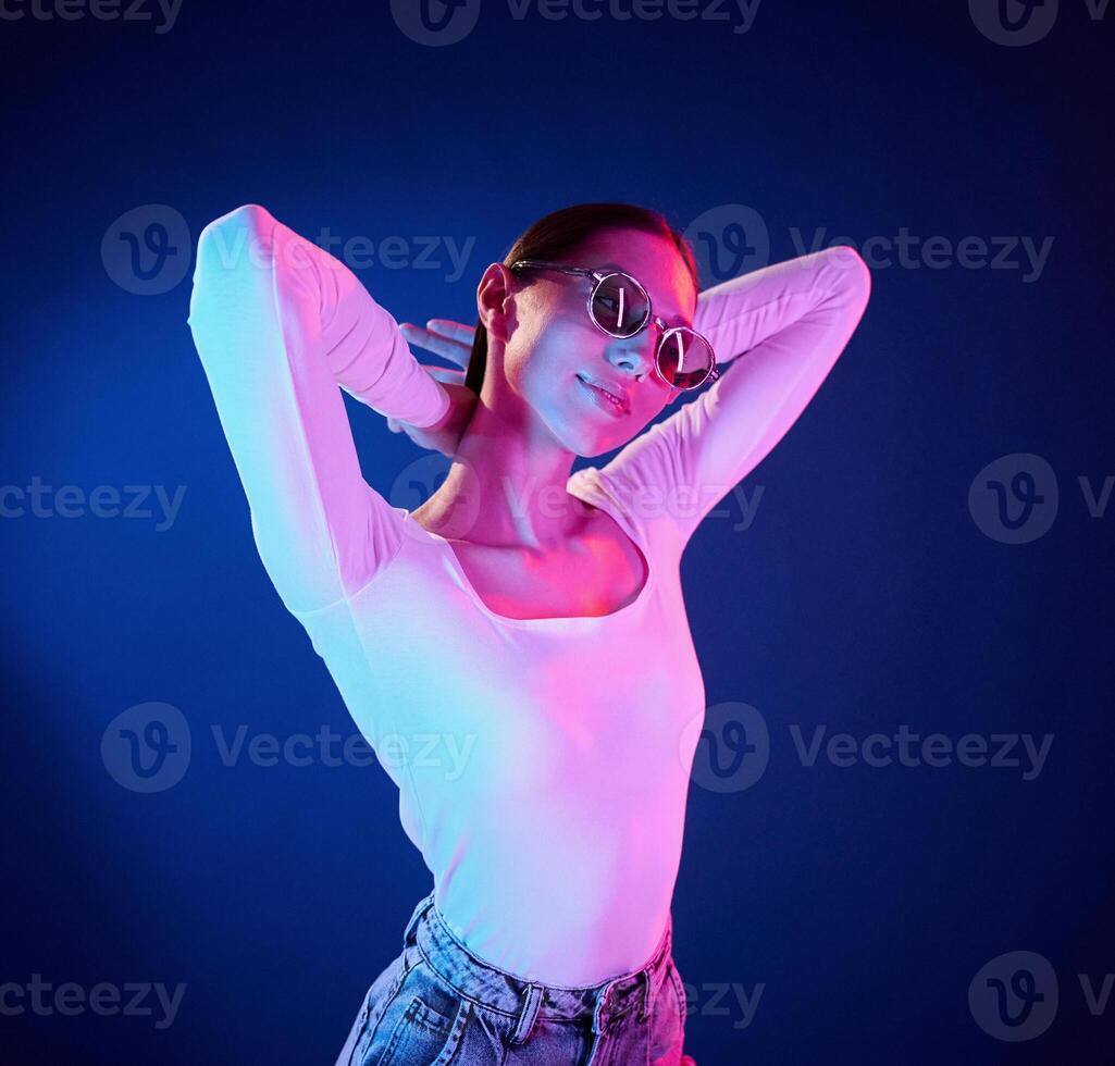 In sunglasses.. Portrait of young woman that is indoors in neon lighting photo