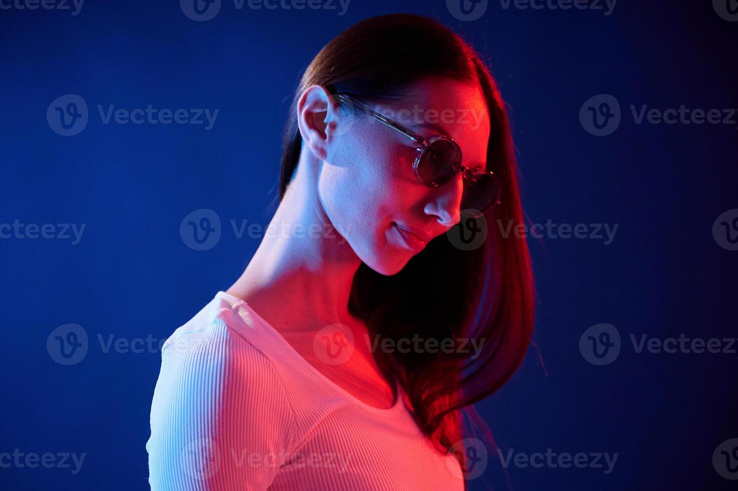 Standing ,and posing. Portrait ,of young woman that is indoors in neon lighting photo
