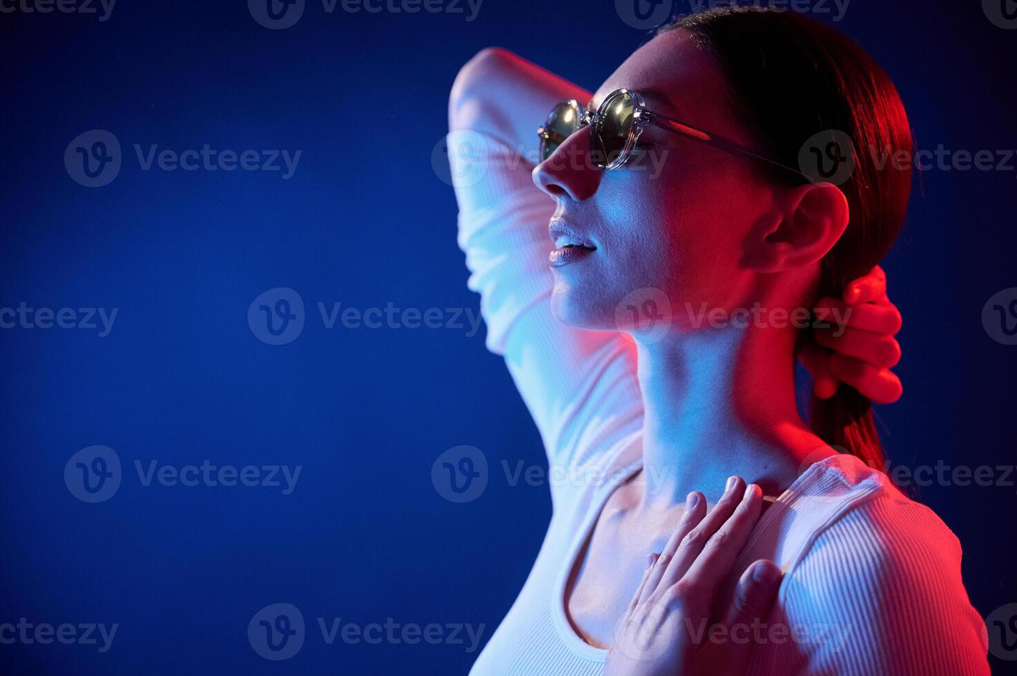 Standing and posing.. Portrait of young woman that is indoors in neon lighting photo