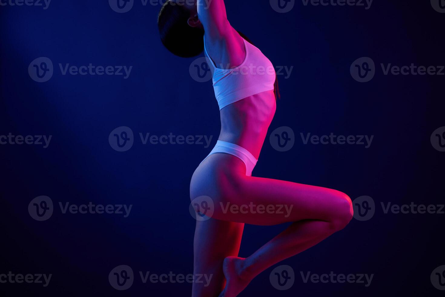 In dark room. Young woman in underwear is in the studio with neon lights. photo