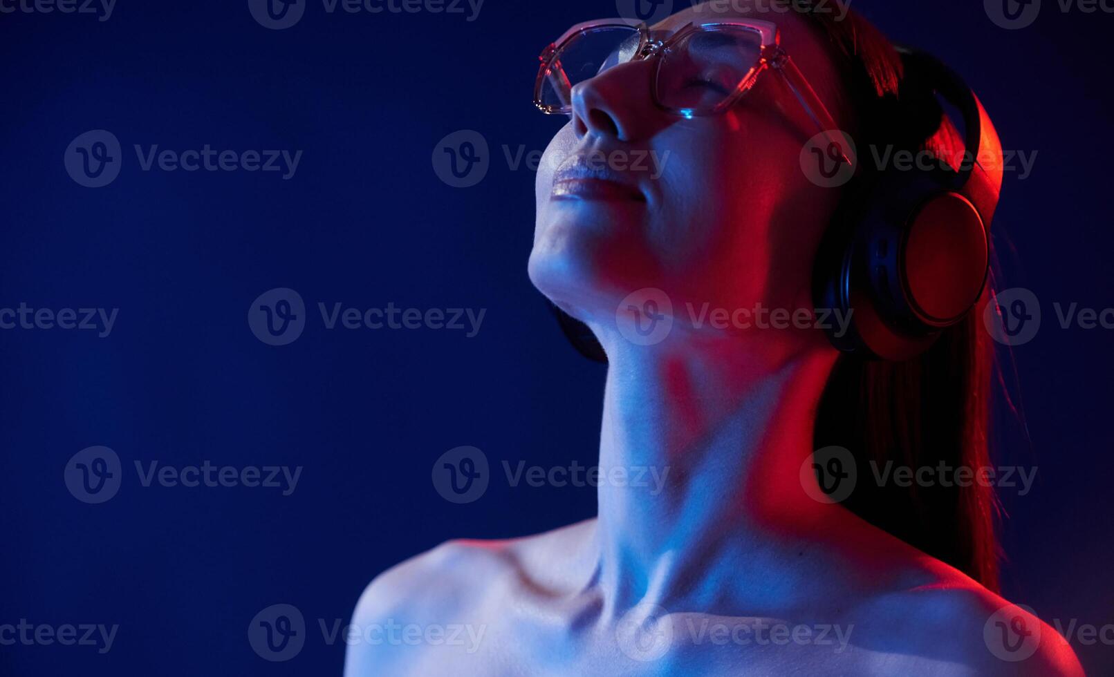 Feel the music. In headphones. Portrait of young woman that is indoors in neon lighting,, photo