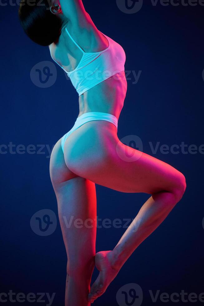 View from the side. .Young woman in underwear is in the studio with neon lights photo