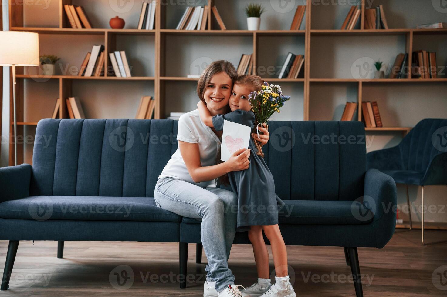 Conception of mother's day. .Giving gift. Young woman with her daughter is together at apartment photo