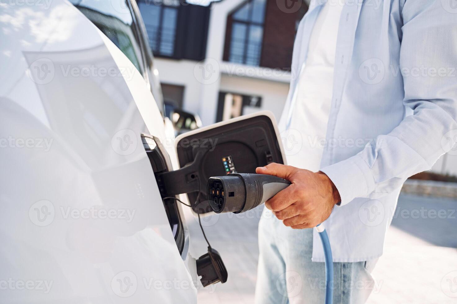 Plugged in charger. Close up view of man with his electric car photo