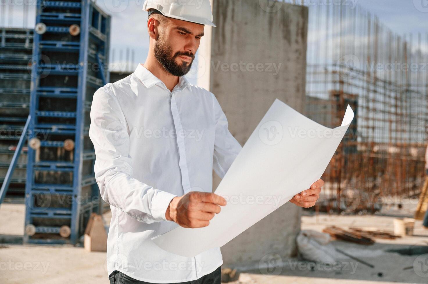 Working with document. Man in uniform is on the construction site.. photo