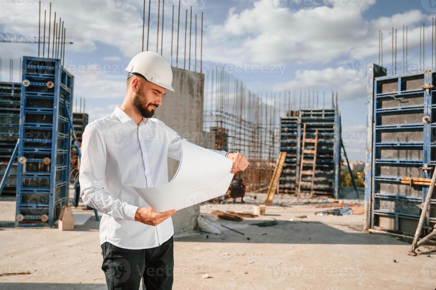 Working with document.. Man in uniform is on the construction site photo