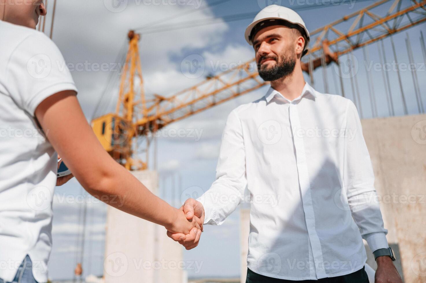 Doing handshake.. Successful agreement. Man in uniform working with woman on the construction site photo