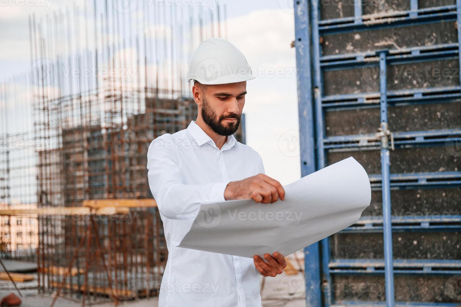 Reading ,the plan. Man, in uniform is working on the construction site photo