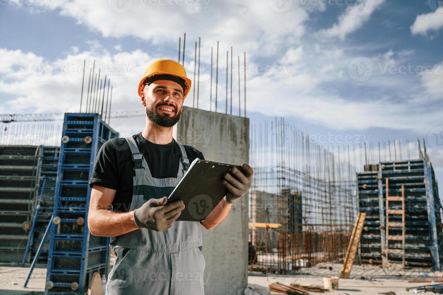 Control of the process.. Foreman is with documents. Man in uniform is working on the construction site photo